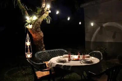 a table with food and plates on it in front of a tree at night at Villa andaluza en zona Playa Barrosa con piscina y barbacoa in Chiclana de la Frontera