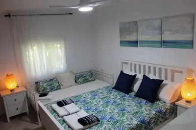 a bedroom with a bed with blue and white pillows at Villa andaluza en zona Playa Barrosa con piscina y barbacoa in Chiclana de la Frontera