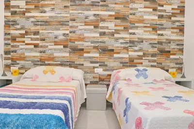 two beds in a room with a brick wall at Chalet Puente Tabla in Conil de la Frontera