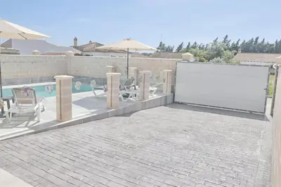 a patio with a white door and chairs and a pool at Chalet Puente Tabla in Conil de la Frontera