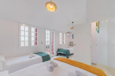a white room with two beds and two windows at Casa Don Camilo Costa Ballena in Costa Ballena