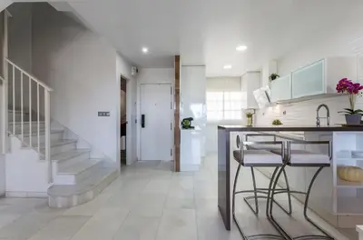 a kitchen with a staircase and a counter with stools at Casa Don Camilo Costa Ballena in Costa Ballena