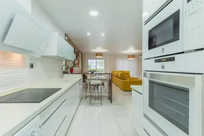 a kitchen with white appliances and a living room at Casa Don Camilo Costa Ballena in Costa Ballena