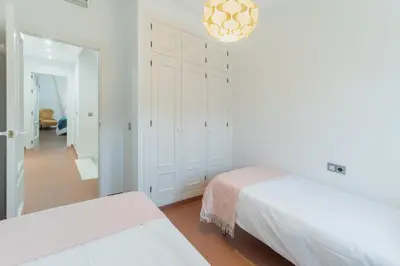 a white bedroom with two beds and a chandelier at Casa Don Camilo Costa Ballena in Costa Ballena