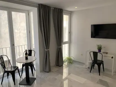 a living room with a table and chairs and a window at San Lorenzo Apartamentos y Suites in Cádiz