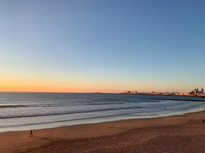 people walking on the beach at sunset at San Lorenzo Apartamentos y Suites in Cádiz
