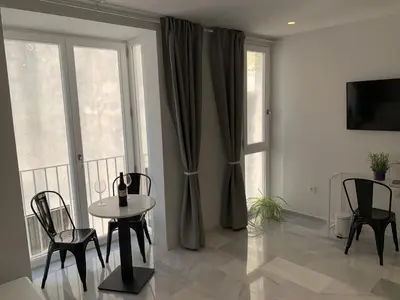 a living room with a table and chairs and a window at San Lorenzo Apartamentos y Suites in Cádiz