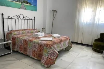 a bedroom with a bed with a blanket and a chair at Mirador Playa Caleta Cádiz Centro Grupo AC Gestion in Cádiz