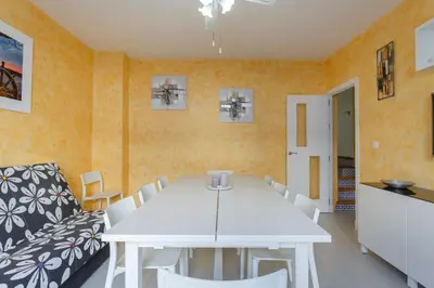 a dining room with a white table and white chairs at La Almadraba in Chiclana de la Frontera