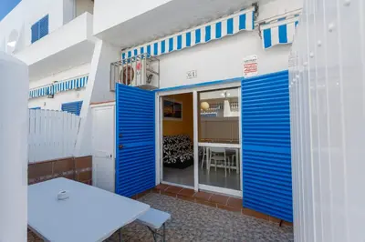 a building with blue and white doors and a table at La Almadraba in Chiclana de la Frontera