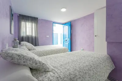 two beds in a bedroom with purple and purple walls at La Almadraba in Chiclana de la Frontera