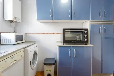 a small kitchen with blue cabinets and a microwave at La Almadraba in Chiclana de la Frontera