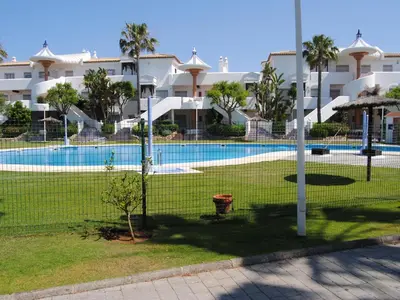 a fence in front of a swimming pool with a resort at Novo Sancti Petri Atardecer planta primera in Chiclana de la Frontera