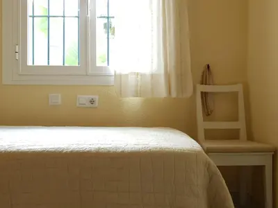 a bedroom with a bed and a window and a chair at Novo Sancti Petri Atardecer planta primera in Chiclana de la Frontera