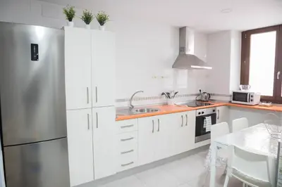 a kitchen with white cabinets and a stainless steel refrigerator at Apartamento Barrocal by Cadiz Time in Cádiz