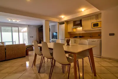 a kitchen with a wooden table and white chairs at Altair 11 in El Puerto de Santa María