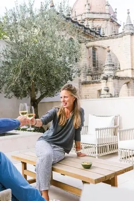 a woman sitting on a picnic table holding a glass of wine at Hotel Bodega Tio Pepe in Jerez de la Frontera