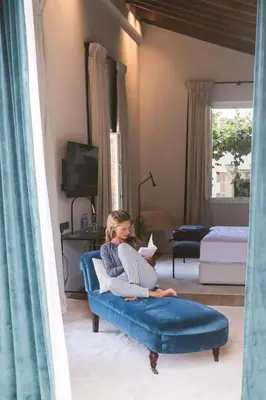 a woman sitting on a blue couch in a living room at Hotel Bodega Tio Pepe in Jerez de la Frontera