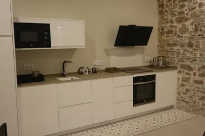 a kitchen with white cabinets and a tv on the wall at LOFTS MIRIAM CONDE O,REILLY in Cádiz