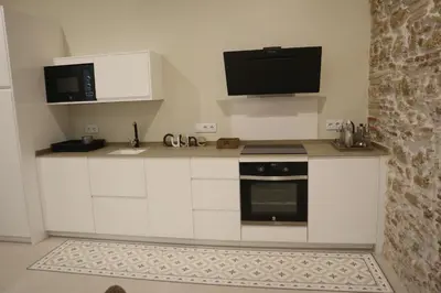a kitchen with white cabinets and a tv on the wall at LOFTS MIRIAM CONDE O,REILLY in Cádiz