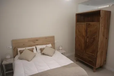 a bedroom with a large bed and a wooden cabinet at LOFTS MIRIAM CONDE O,REILLY in Cádiz