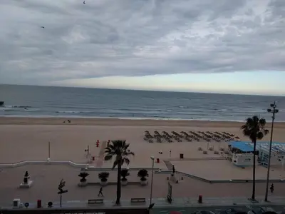 a beach with chairs and palm trees and the ocean at Novo Sancti Petri - Playa, Piscina, Golf y Relax in Chiclana de la Frontera