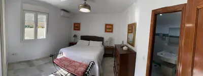 a bedroom with a bed and a bathroom with a sink at Bonito Ático en el centro de la ciudad in Sanlúcar de Barrameda