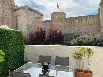a balcony with a glass table in front of a castle at Bonito Ático en el centro de la ciudad in Sanlúcar de Barrameda