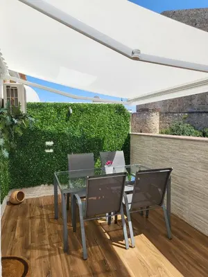 a patio with a glass table and chairs at Bonito Ático en el centro de la ciudad in Sanlúcar de Barrameda