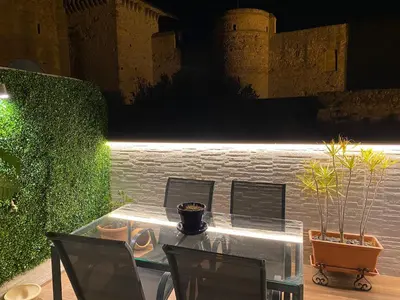 a glass table with chairs and plants on a patio at Bonito Ático en el centro de la ciudad in Sanlúcar de Barrameda