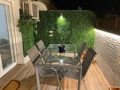 a table and chairs in front of a green wall at Bonito Ático en el centro de la ciudad in Sanlúcar de Barrameda