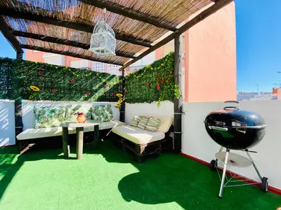 a patio with a couch and a table and a grill at Ramón y Cajal 6 in Chipiona