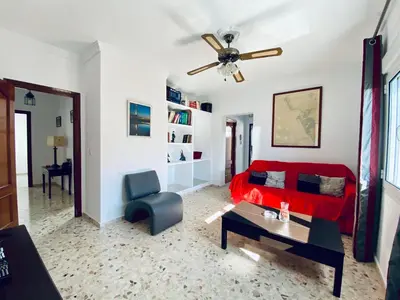 a living room with a red couch and a ceiling fan at Ramón y Cajal 6 in Chipiona
