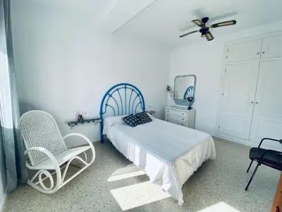 a bedroom with a bed and two chairs and a ceiling fan at Ramón y Cajal 6 in Chipiona