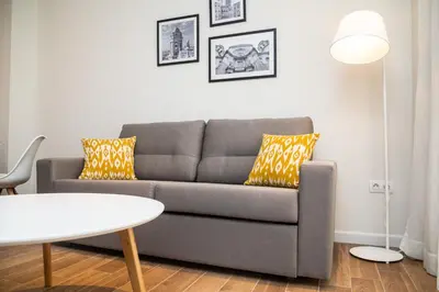 a living room with a gray couch with yellow pillows at Tandem Puerto Chico in Cádiz