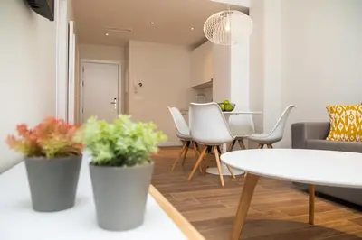 a living room with a table and white chairs at Tandem Puerto Chico in Cádiz
