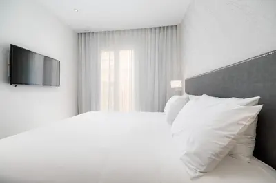 a white bedroom with a bed with white pillows at Tandem Puerto Chico in Cádiz