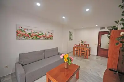 a living room with a couch and a table with flowers at Playa Santa María 3 Dormitorios 2 Baños in Cádiz