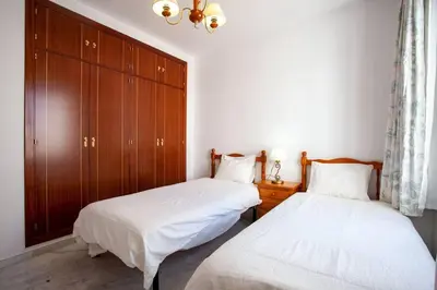 a bedroom with two beds and a wooden cabinet at Sanlucar Misericordia Centro in Sanlúcar de Barrameda