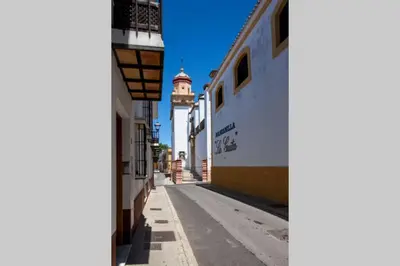 an empty street with a clock tower in the distance at Sanlucar Misericordia Centro in Sanlúcar de Barrameda