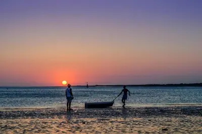 two people on the beach with a boat at sunset at Sanlucar Misericordia Centro in Sanlúcar de Barrameda