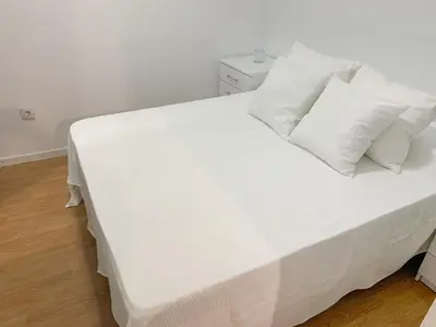 a bed with white sheets and pillows in a room at Apartamento Centro Costa de la Luz in Sanlúcar de Barrameda