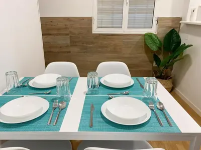 a dining table with white plates and silverware on it at Apartamento Centro Costa de la Luz in Sanlúcar de Barrameda