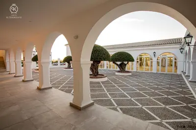 a courtyard with arches and potted trees in a building at El Tesorillo II in Arcos de la Frontera