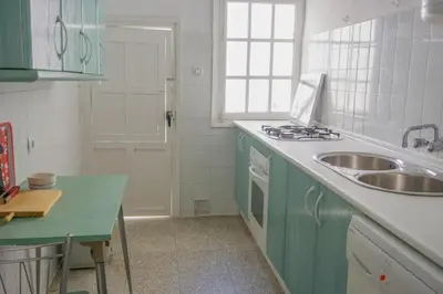 a kitchen with green cabinets and a sink and a stove at Amplio alojamiento con magnificas vista a 6 metros de la playa in Chipiona