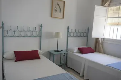a bedroom with two beds and a table with a lamp at Amplio alojamiento con magnificas vista a 6 metros de la playa in Chipiona