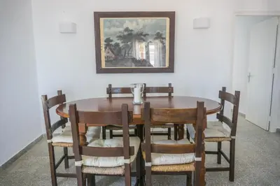 a dining room table with chairs and a painting on the wall at Amplio alojamiento con magnificas vista a 6 metros de la playa in Chipiona