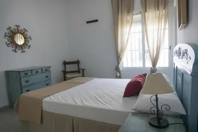 a bedroom with a bed and a dresser and a window at Amplio alojamiento con magnificas vista a 6 metros de la playa in Chipiona