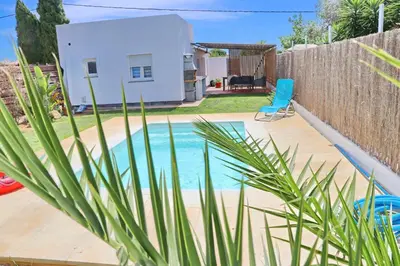 a swimming pool in a backyard with a blue chair at Chalet Isla Azul in Chiclana de la Frontera