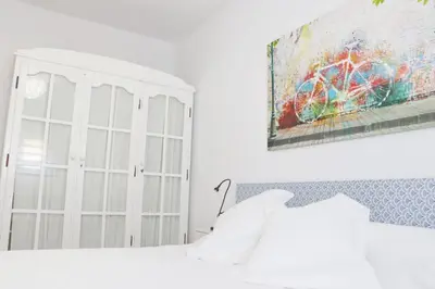 a bedroom with a white bed and a painting on the wall at Chalet Isla Azul in Chiclana de la Frontera